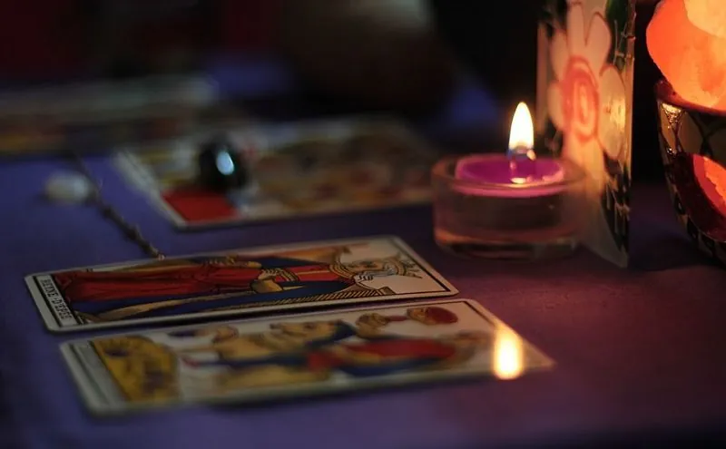 Cartas del tarot de Marsella sobre mesa morada con velas