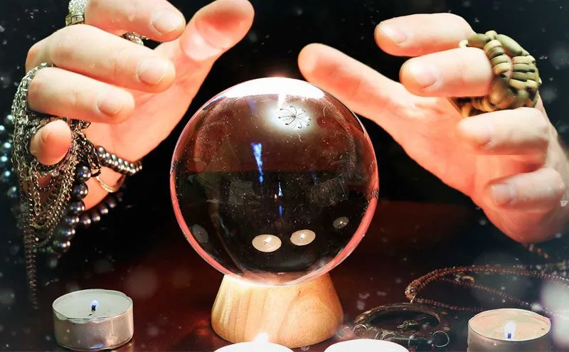 Tarot bueno y fiable: manos rodeando una bola de cristal entre velas