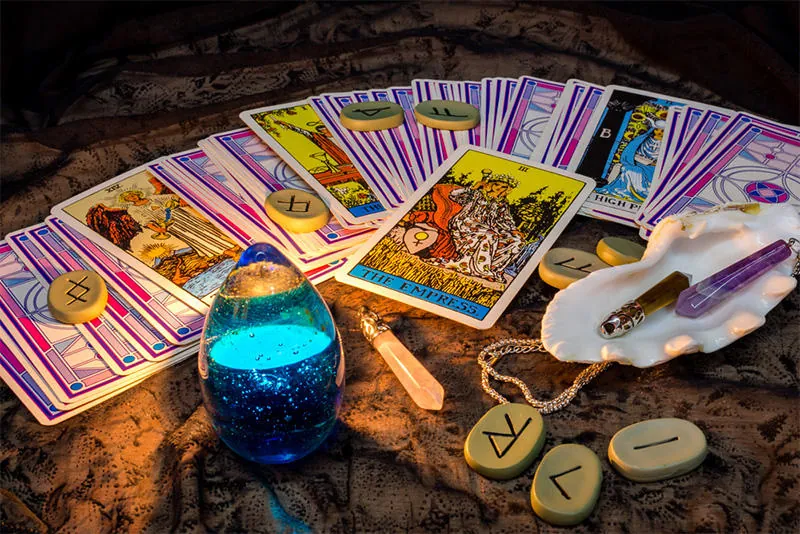Tarot económico y fiable: cartas en abanico con vela azul, runas y cuarzo