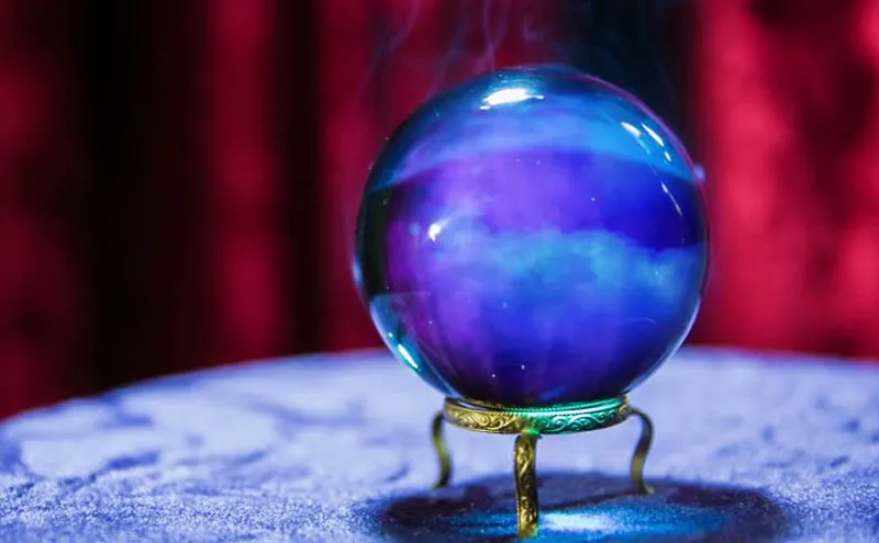 Videncia por teléfono: bola de cristal azul sobre soporte dorado