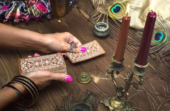 Vidente buena y económica trabajando con cartas, velas y plumas de pavo real