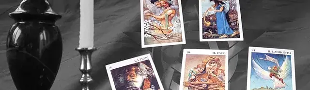 Vidente buena real: jarrón negro, vela blanca y cartas sobre un paño gris
