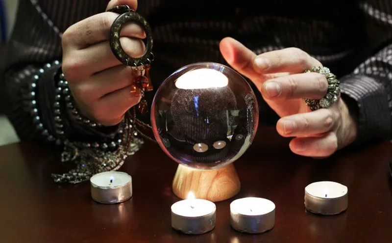 Vidente económica: manos con anillos alrededor de una bola de cristal