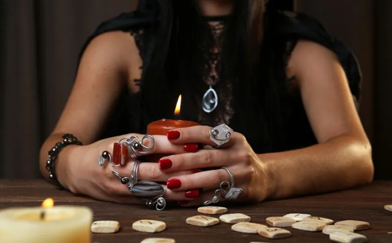 Vidente con vela roja y runas sobre la mesa